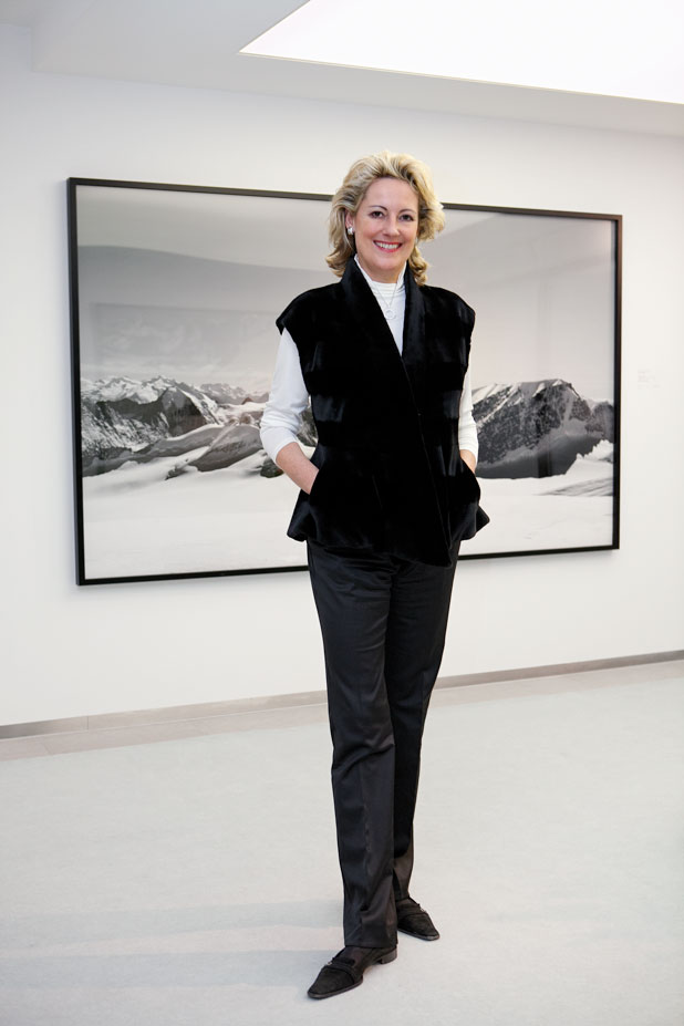 Irène Schönholzer - Die Kunsthändlerin und Galeristin in schwarzem Kleid steht vor einem Bild